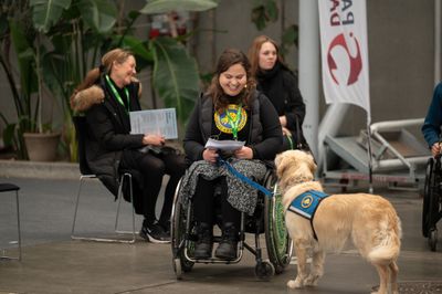 Kvinde i kørestol med servicehund på messen